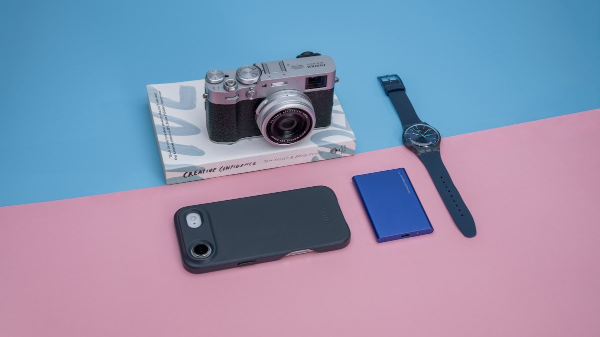Objetos falantes com IA: câmera, relógio e celular sobre fundo colorido